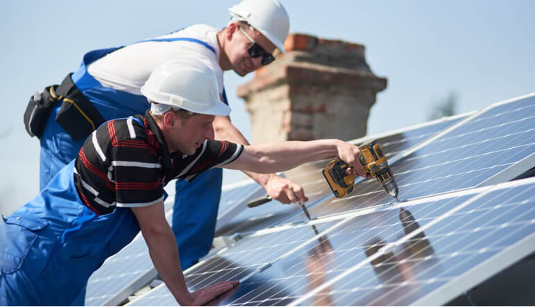 Electricians installing solar panels on a roof.